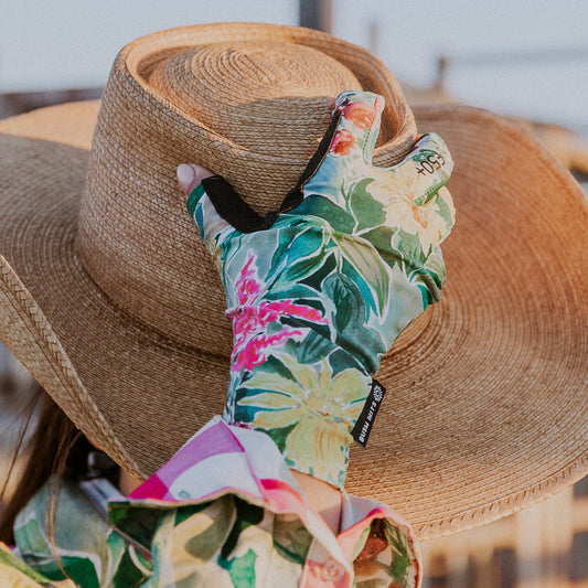 Person wearing a wide-brimmed hat with colorful  and floral sun protection gloves