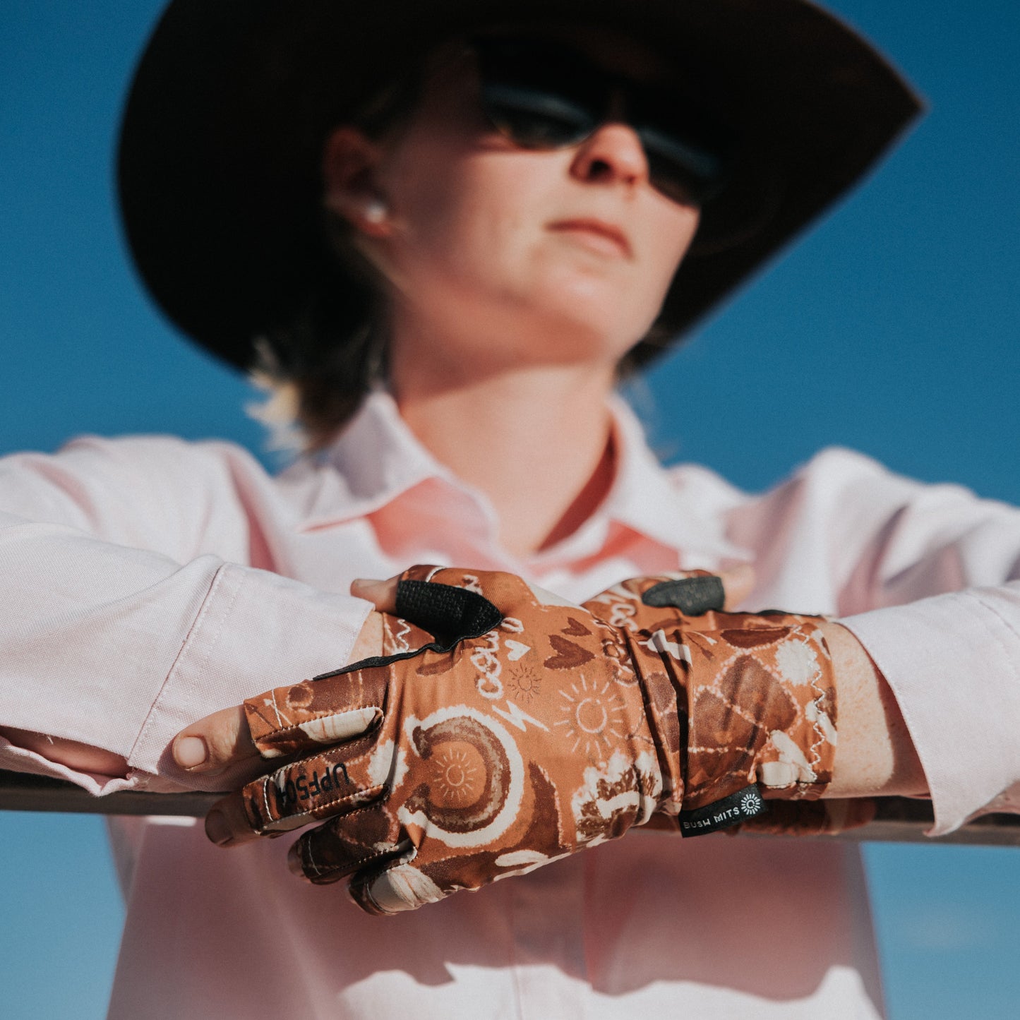 Person wearing a Dust Off western gloves against a clear blue sky